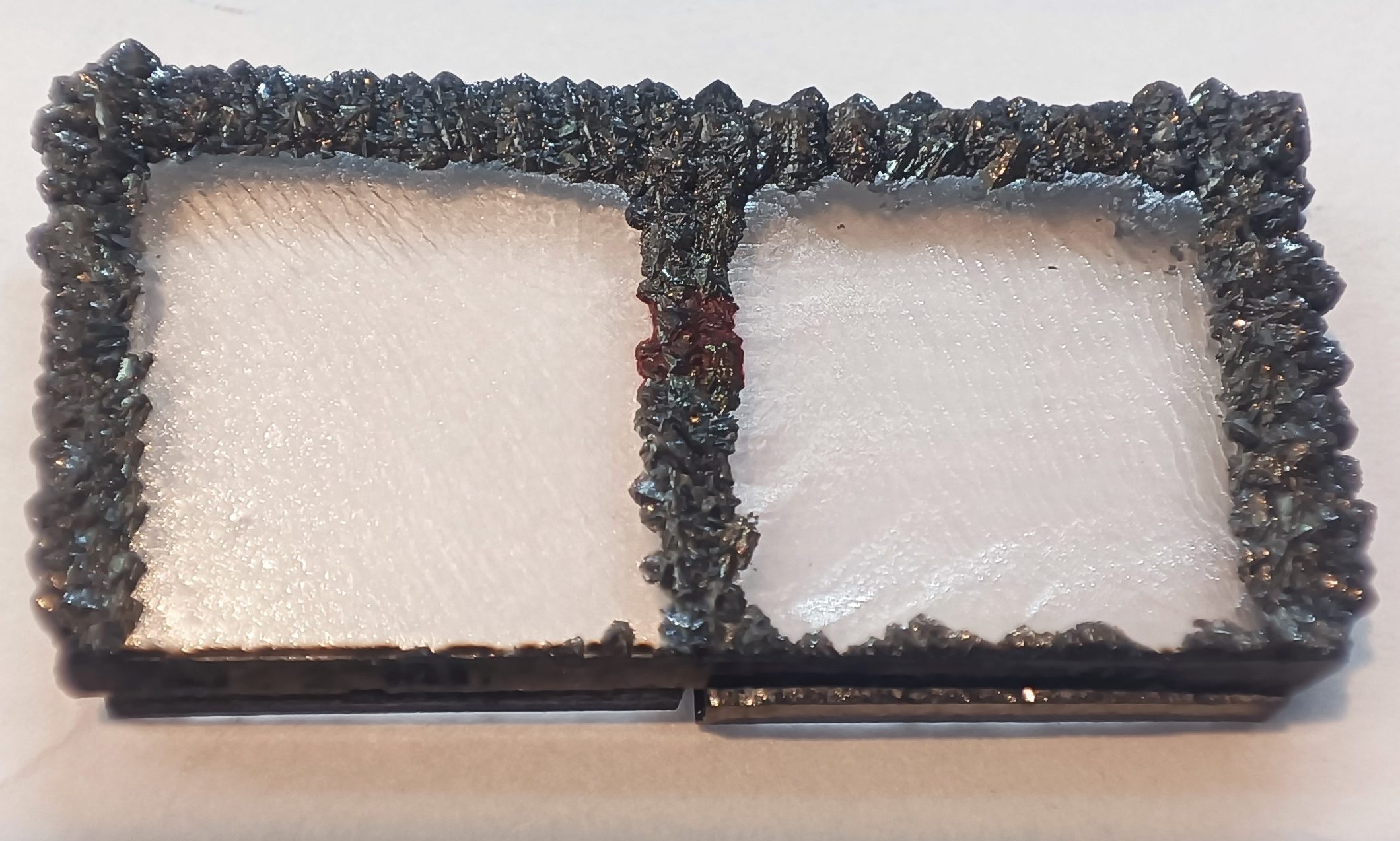 A rectangular sample consisting of two white CVD‑grown surfaces framed by a dark, rough polycrystalline diamond border.