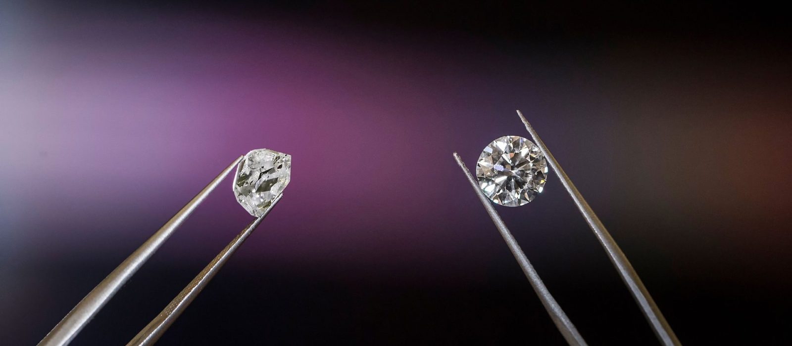 Two tweezers hold two diamonds side by side: a rough, uncut stone on the left and a polished, round‑brilliant diamond on the right, against a soft purple gradient background.